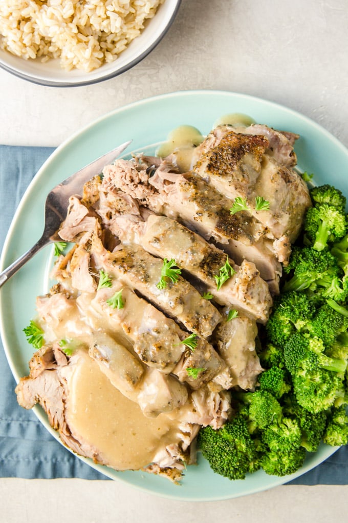 Overhead shot of crock pot pork roast with gravy and broccoli.