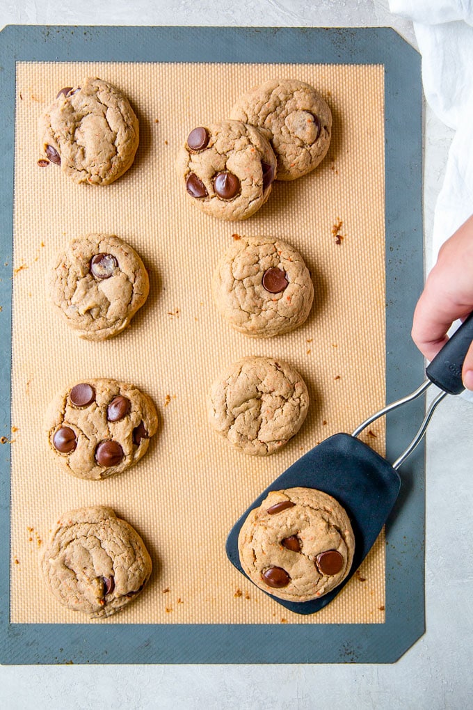 Carrot Cake Cookies on a baking sheet with a spatula lifting one cookie