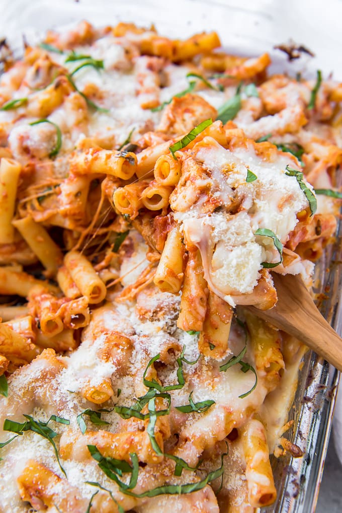 Baked Ziti on a wooden spoon sitting on a ziti casserole.