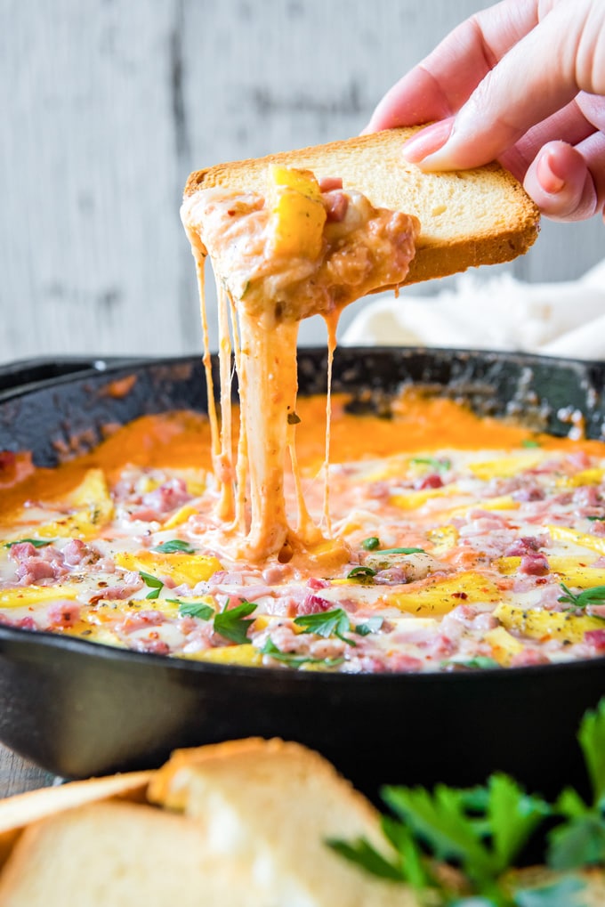 Bread dipping into pan of Hawaiian Pizza Dip