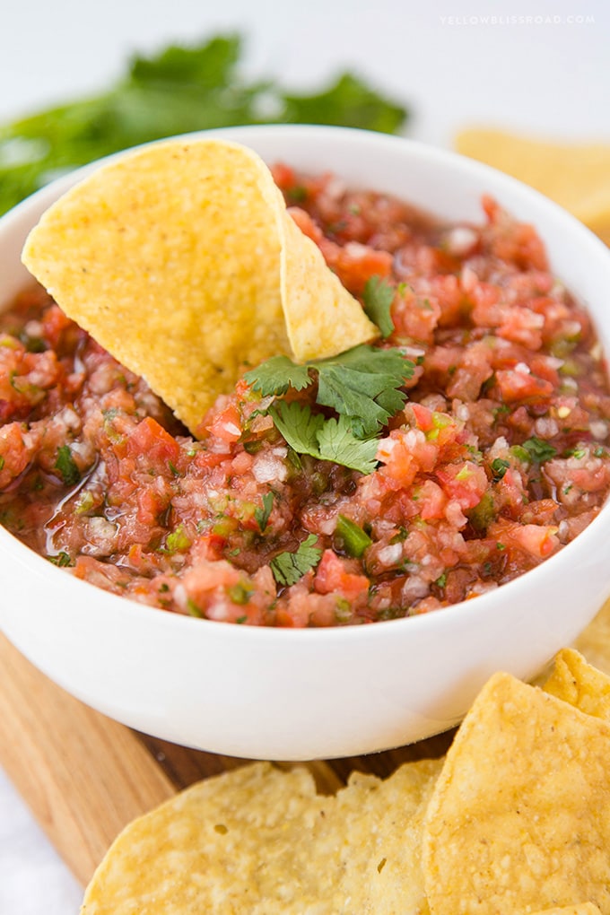 A bowl of homemade salsa with a tortilla chip in it