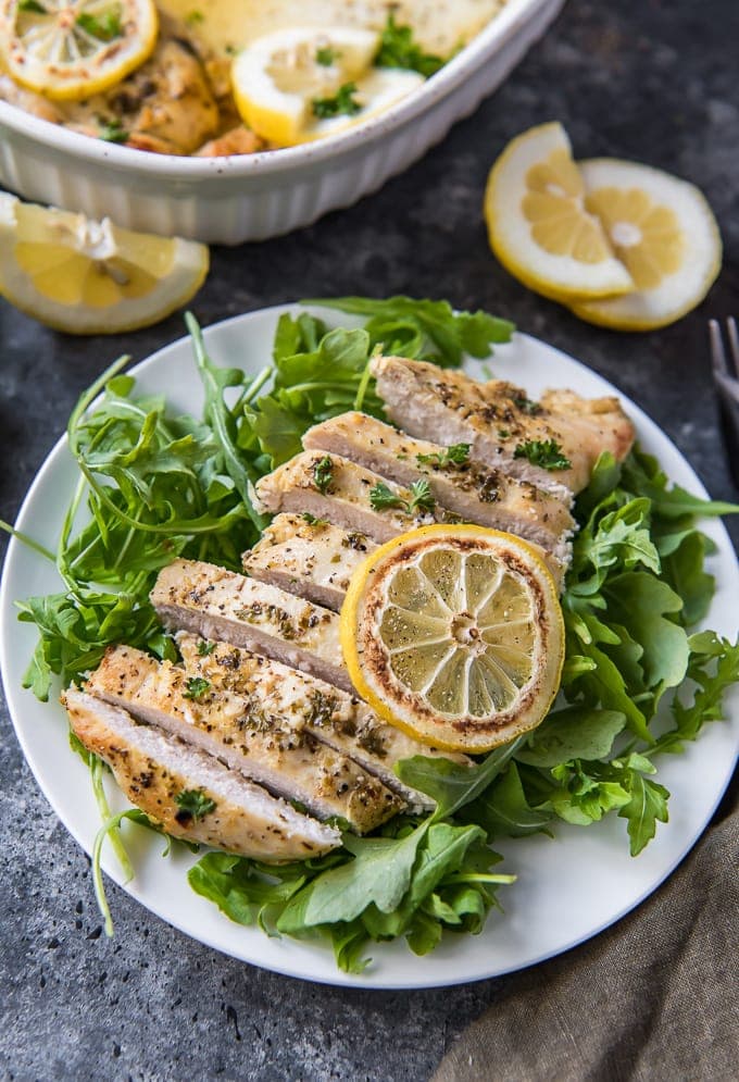 A bowl of salad on a plate, with Lemon and Chicken