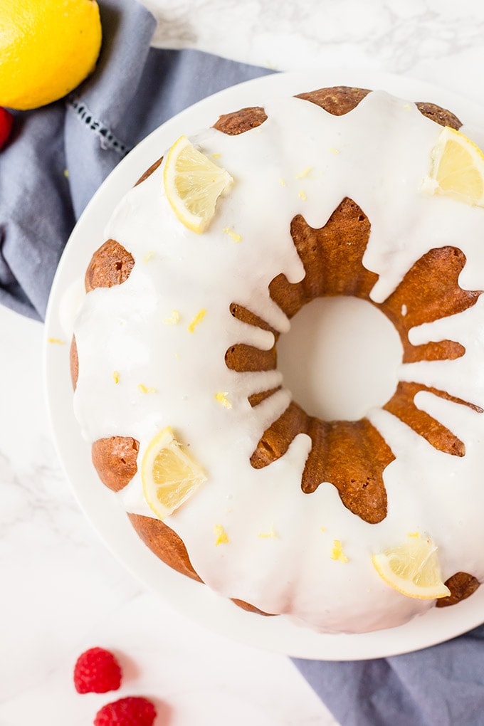 An overhead shot of a lemon bundt cake with white icing and lemon slices