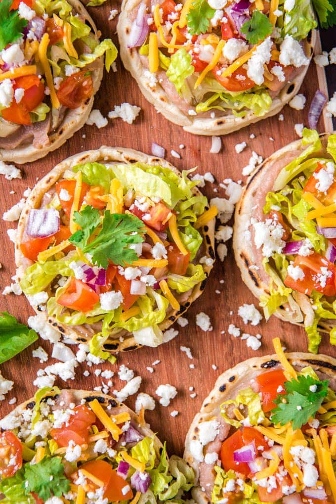 Authentic Sopes are a traditional Mexican dish that's perfect for Cinco de Mayo! Top them with beans, meat and vegetables for a delicious snack or meal. An overhead close up of mexican sopes