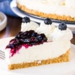 A slice of no bake blueberry cheesecake with a graham cracker crust and juicy blueberry topping.