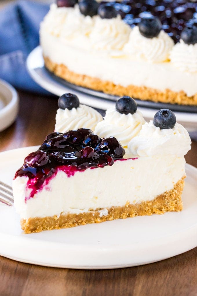 A slice of no bake blueberry cheesecake with a graham cracker crust and juicy blueberry topping. 