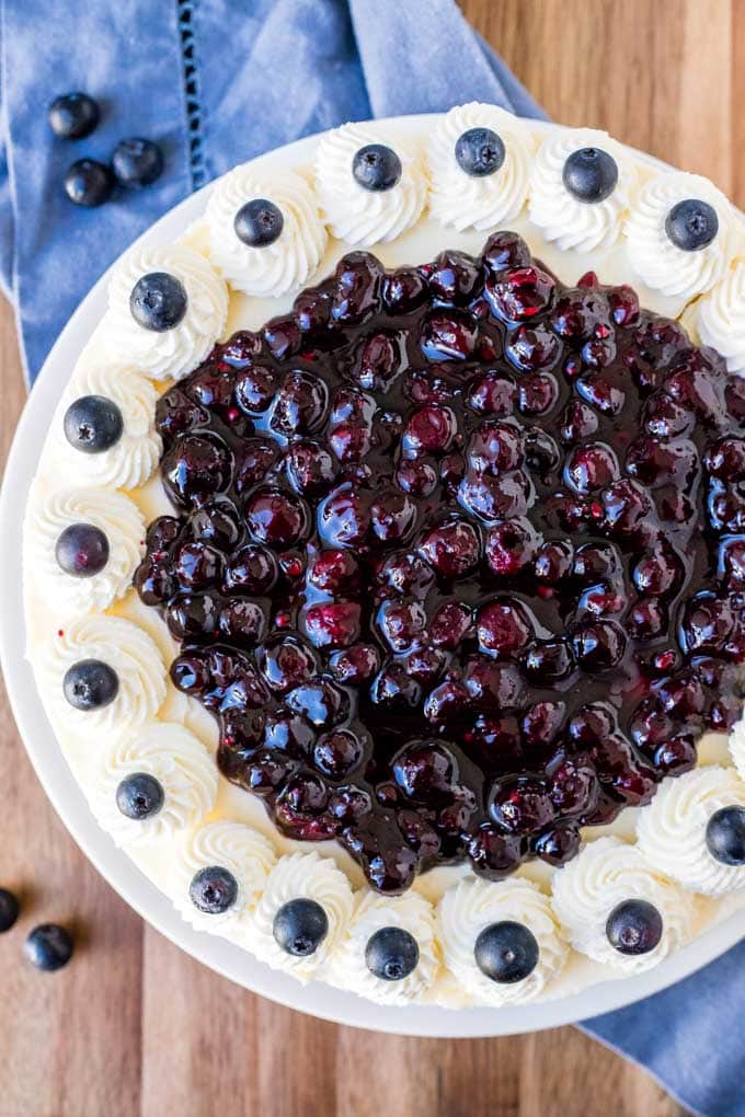 This No Bake Blueberry Cheesecake is extra creamy with a crunchy graham cracker crust and juicy blueberry topping! Perfect for summer parties and BBQs. Overhead shot of a no bake blueberry cheesecake.