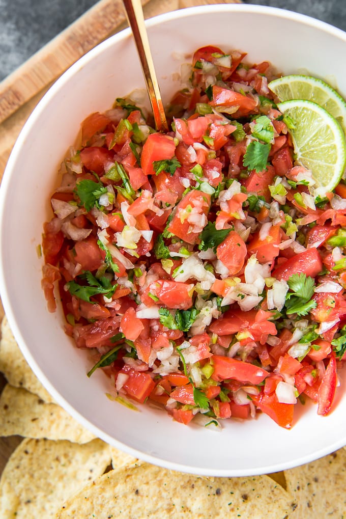 Salsa fresca (pico de gallo) in a large white bowl with a gold spoon.