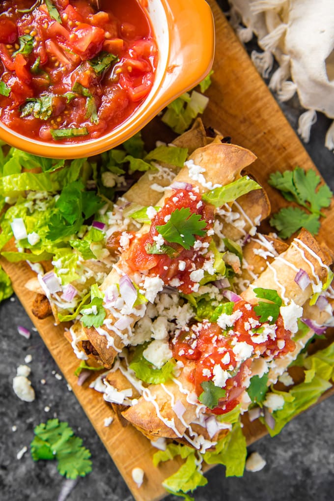 An overhead shot of homemade taquitos with a side of salsa.