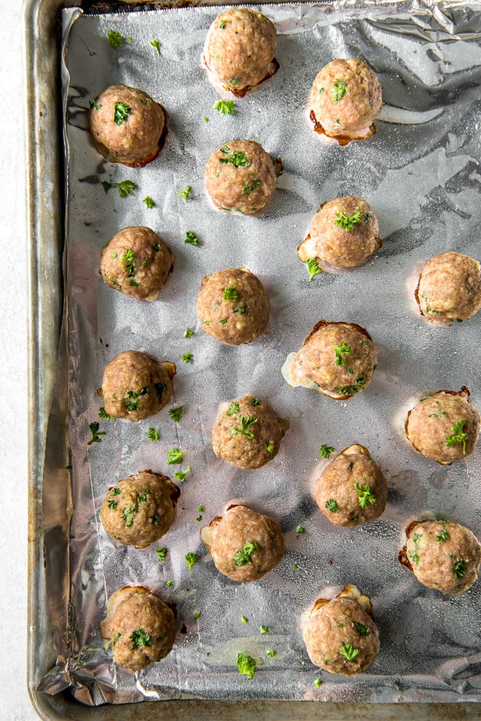 These Ground Turkey Meatballs are tender and moist and a great way to eat healthier without sacrificing flavor! Add them to soups, sandwiches and more! A cookie sheet with cooked turkey meatballs
