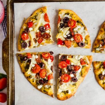 An overhead image of flatbread pizza sliced into quarters