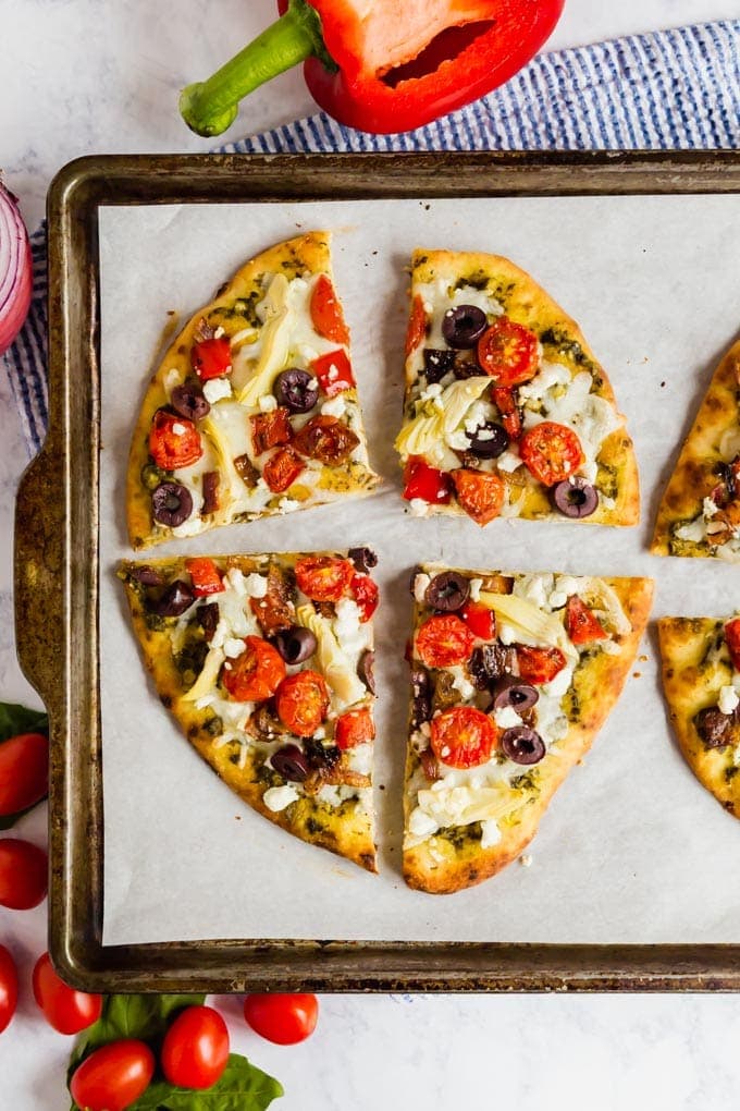 An overhead image of flatbread pizza sliced into quarters