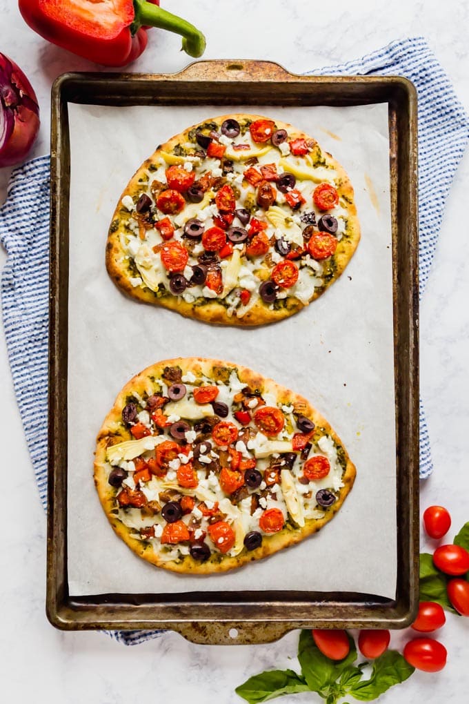 A overhead image of a pan with two whole flatbread pizzas