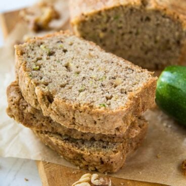 slices of zucchini bread stacked on a wood cutting board