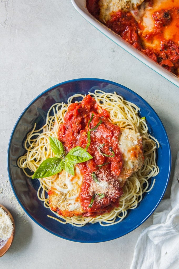 A plate chicken parmesan and spaghetti noodles.