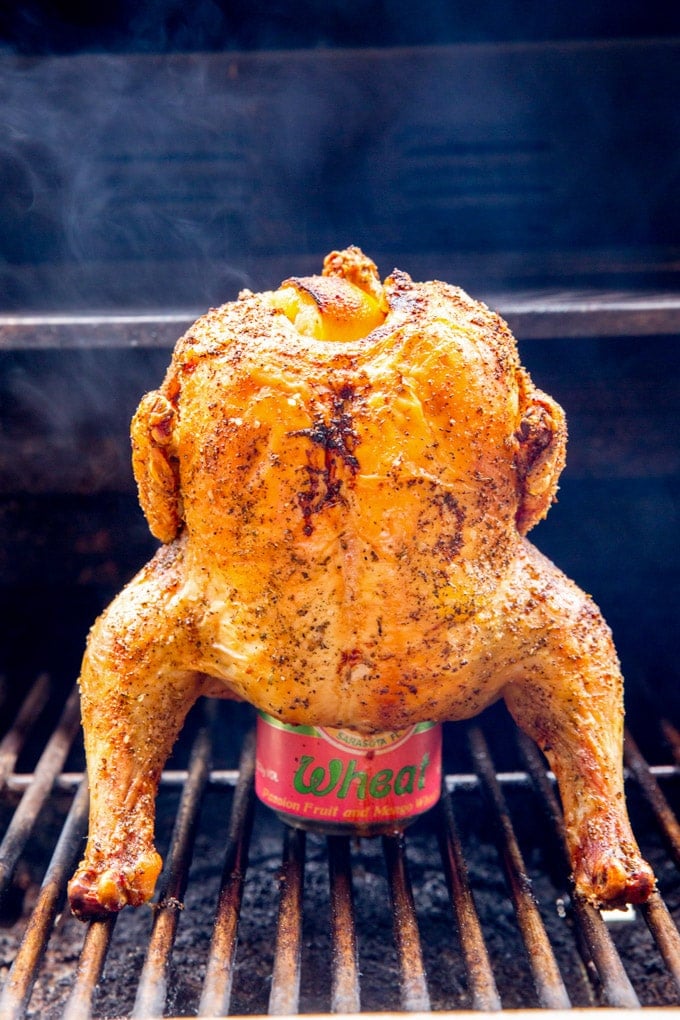 A whole chicken cooking on the grill while sitting on top of a beer can. A whole chicken cooking on the grill while sitting on top of a beer can.