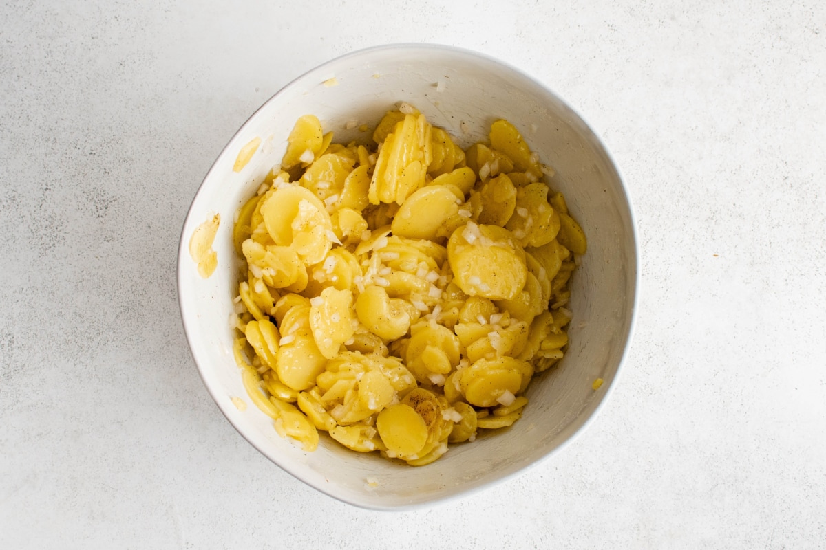 Sliced potaotes and diced onions in a bowl.