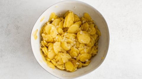 Sliced potaotes and diced onions in a bowl.