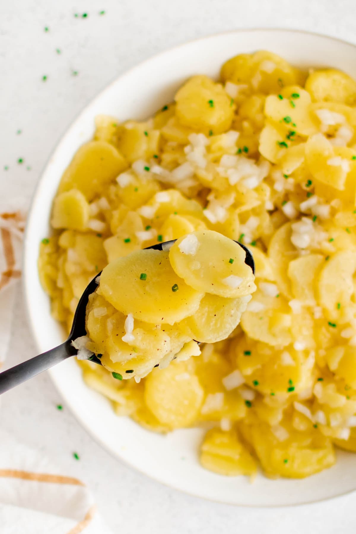 A large serving spoon with potato salad on it.