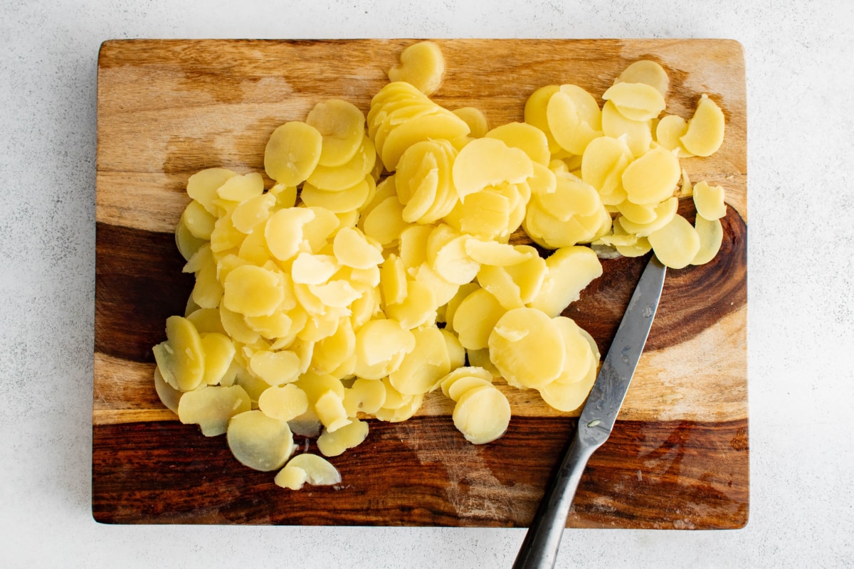 Sliced potatoes on a wood cutting board.