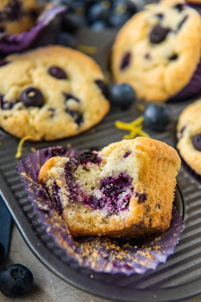 A lemon blueberry muffin sitting sideways with a bit taken out of it.