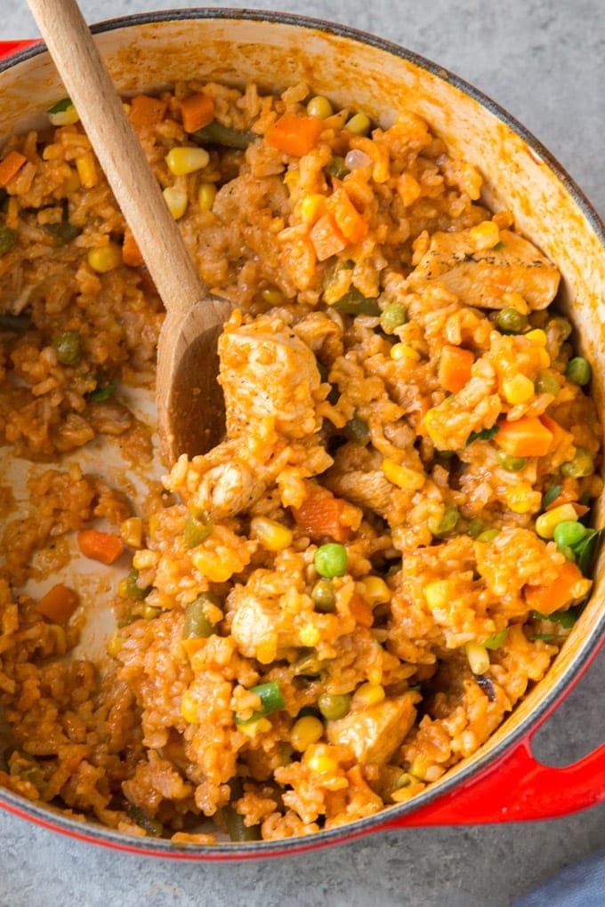 A large pot of Mexican Chicken and Rice with a wooden spoon for stirring.