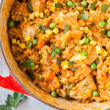 Pot filled with rice, chicken, peas, carrots, and corn.