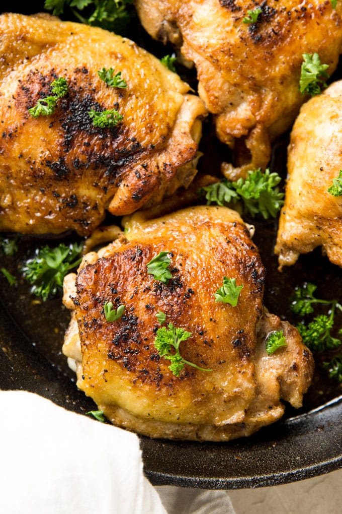 Pan Roasted Chicken Thighs in a cast iron skillet garnished with parsley