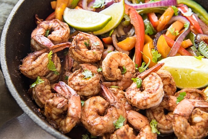 Shrimp, peppers and lime in a cast iron skillet to make shrimp fajitas