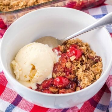 square image of cherry crisp in a bowl