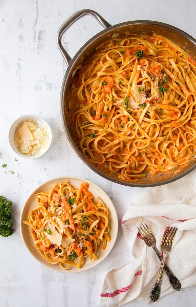 A pan and a plate full of red pepper fettuccine and parmesan