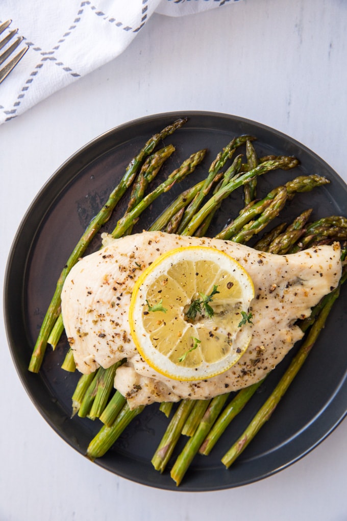 Chicken on top of asparagus on a plate