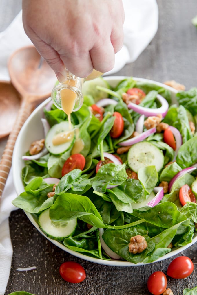 Dressing being poured over spinach salad