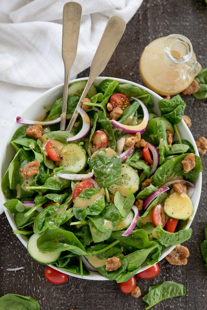 Spinach Salad with Red Wine Vinaigrette is the best weekday salad! It's easy and fast, made with fresh spinach, tomatoes, cucumbers and crunchy walnuts. Spinach, cucumbers, onions and tomatoes in a white bowl with silver spoons.