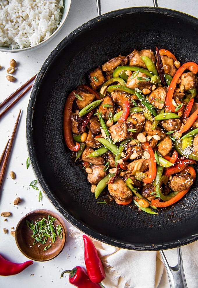 A large wok with chicken, vegetables and szechuan sauce.