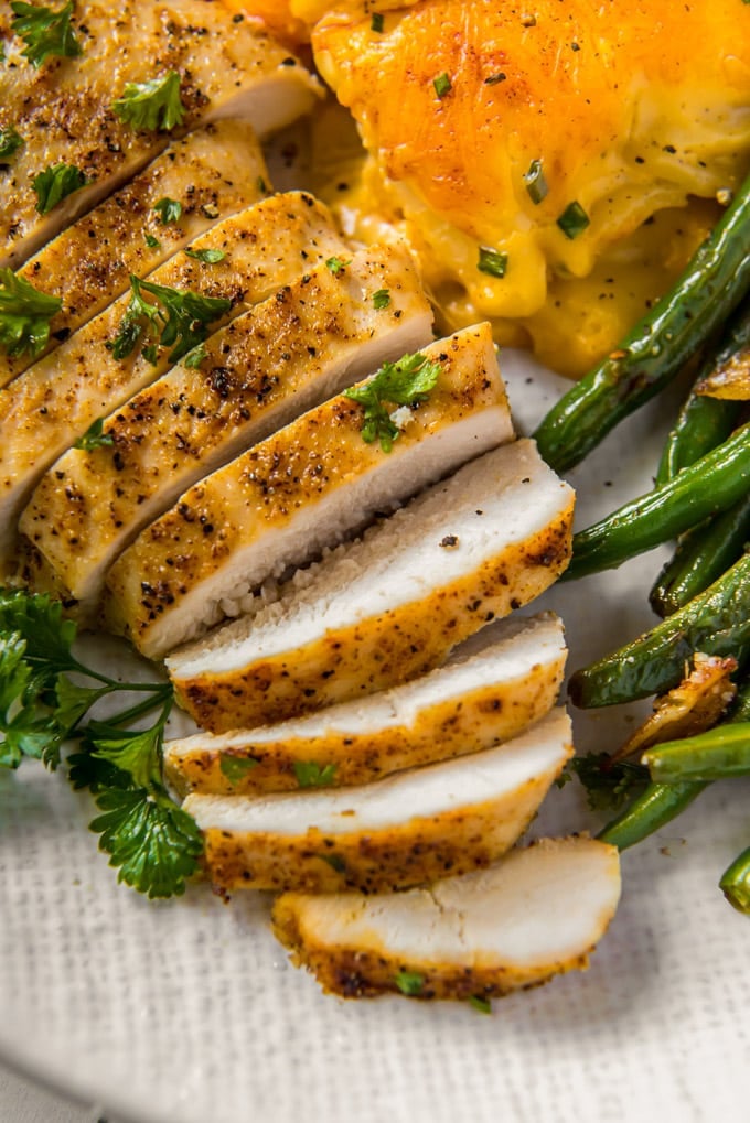 sliced chicken on a white plate with green beans and potatoes