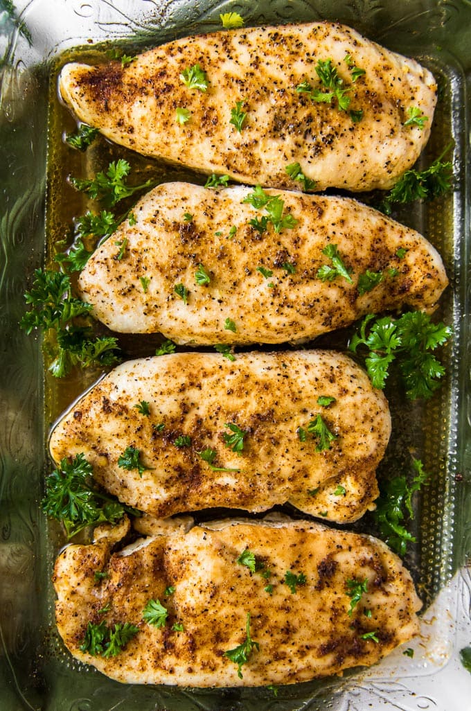 A glass dish with 4 baked chicken breasts