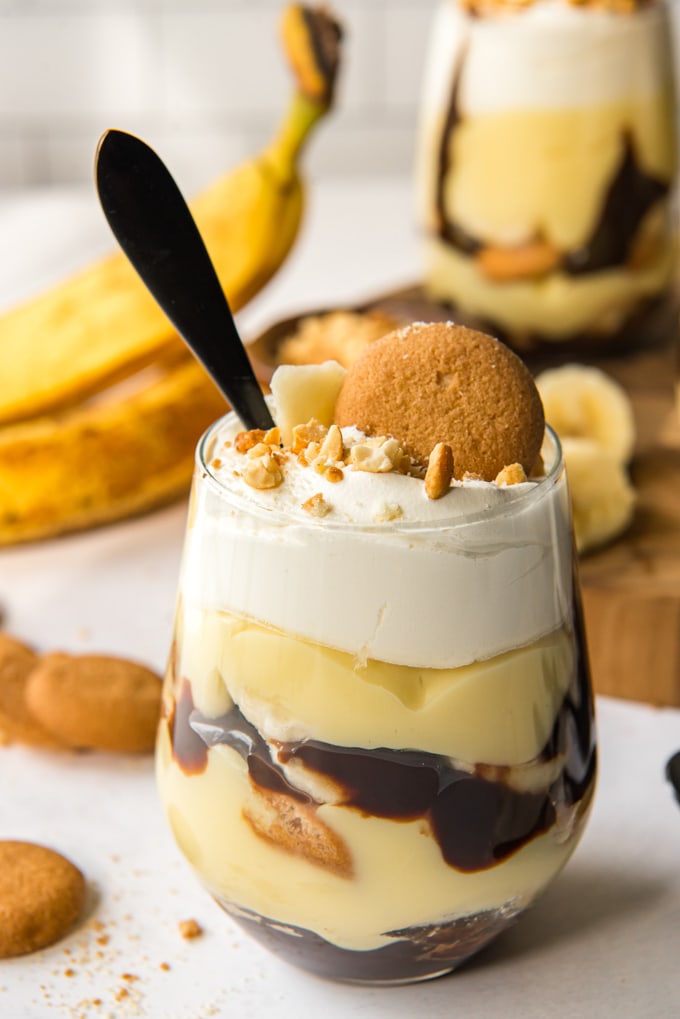 Vanilla pudding layered with bananas, chocolate and vanilla wafers in a clear glass.