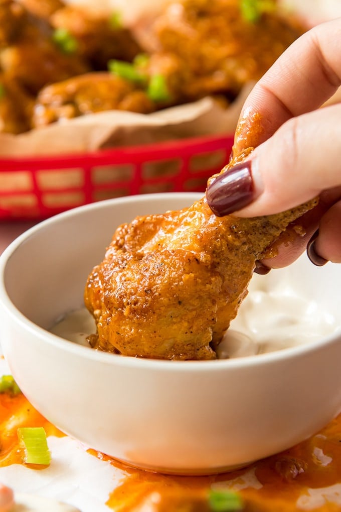 hand dipping a chicken wing in ranch dressing