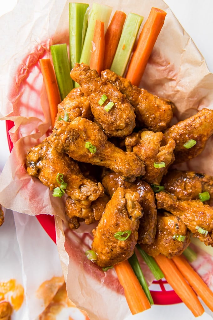 baked chicken wings in a red basket with carrot and celery stiskc