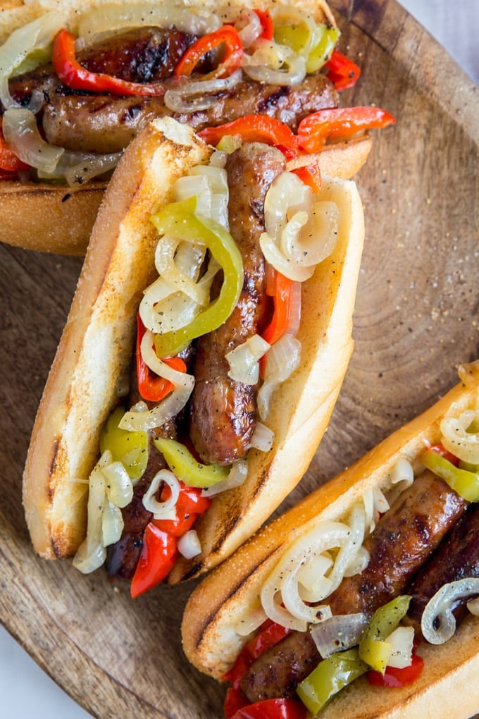 An overhead photo of toasted rolled filled with sausage, peppers and onions.