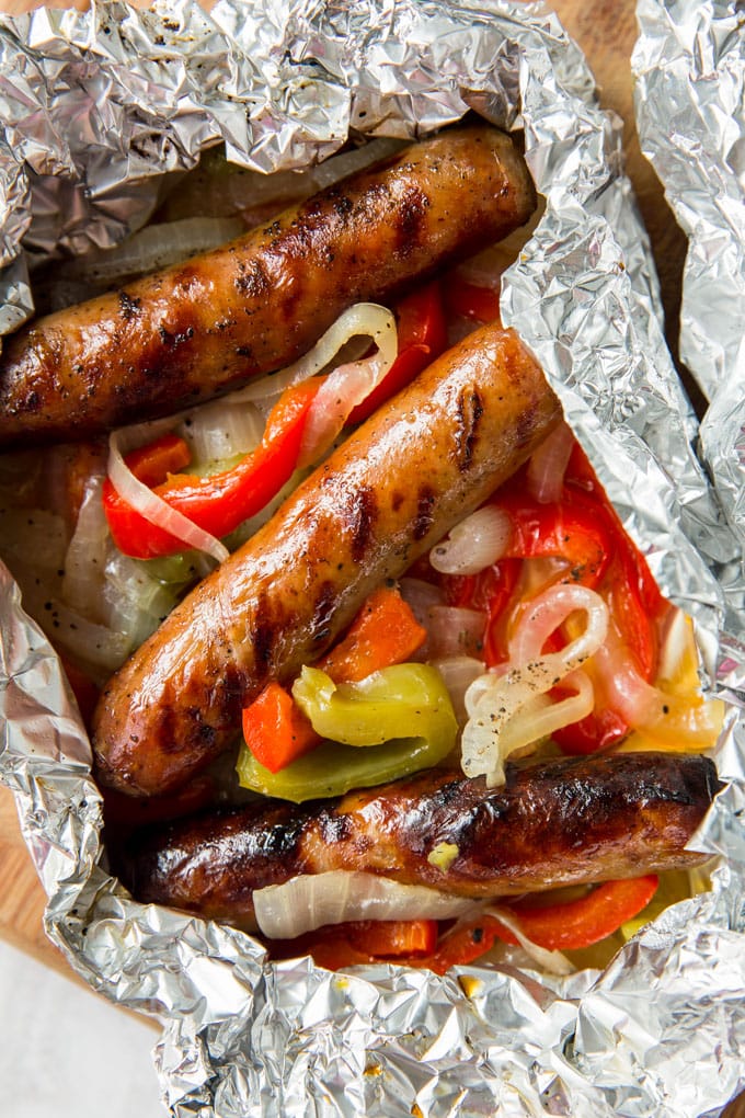 Three sausages and peppers and onions wrapped in foil.