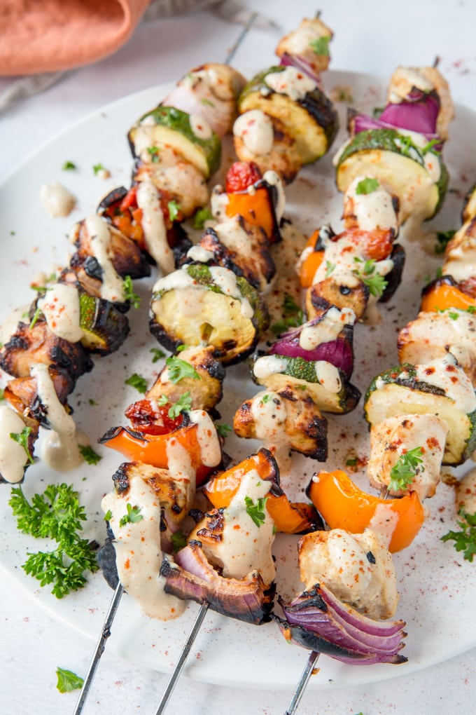 4 skewers (kabobs) with chicken chunks, bell pepper, onion and zucchini. Parsley garnish.