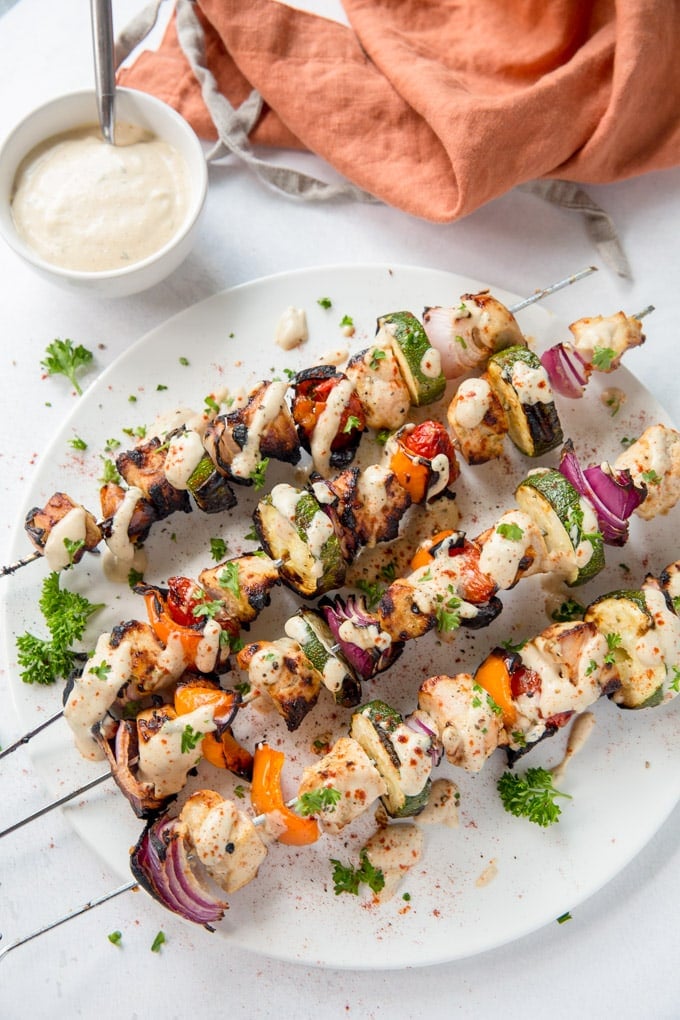 Garlic Lime Chicken Kabobs are perfect for grilling season! Chicken and veggies drizzled with a tangy, creamy garlic lime dressing are the perfect dinner. Chicken and vegetables on skewers and coated in garlic lime dressing.