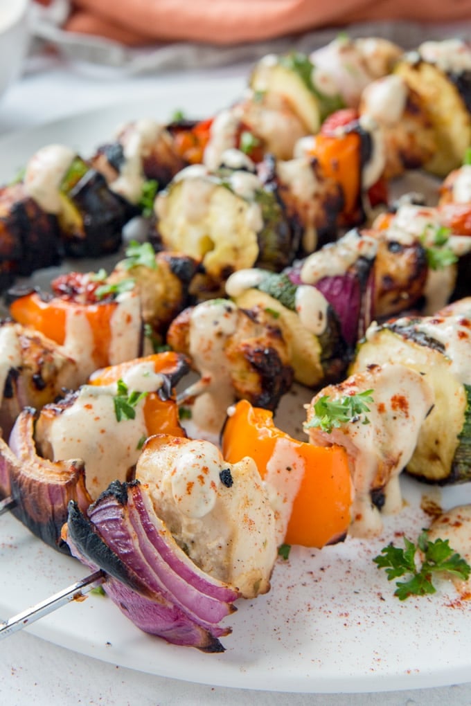Garlic Lime Chicken Kabobs are perfect for grilling season! Chicken and veggies drizzled with a tangy, creamy garlic lime dressing are the perfect dinner. A close up of chicken and veggie skewers