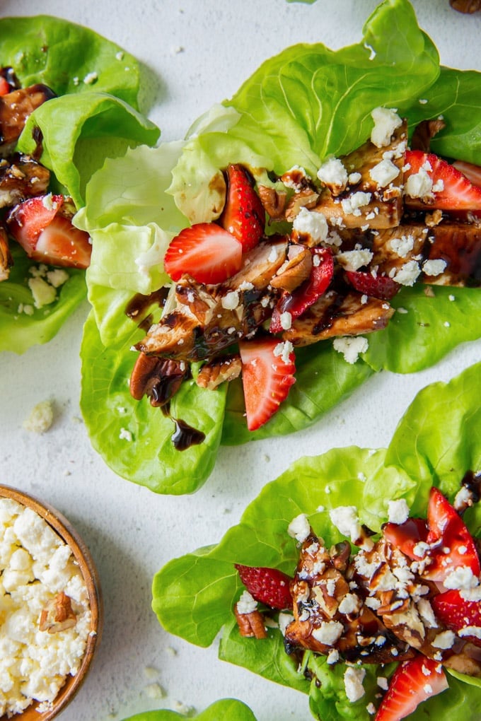 Grilled Balsamic Chicken in a tangy orange balsamic marinade with strawberries, pecans and Feta. These lettuce wraps are a light and filling summer meal. A close up image of a lettuce wrap filled with balsamic chicken