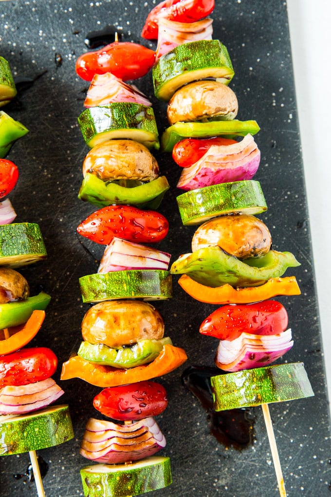 Vegetables on skewers that have been coated with balsamic vinegar, ready to grill.