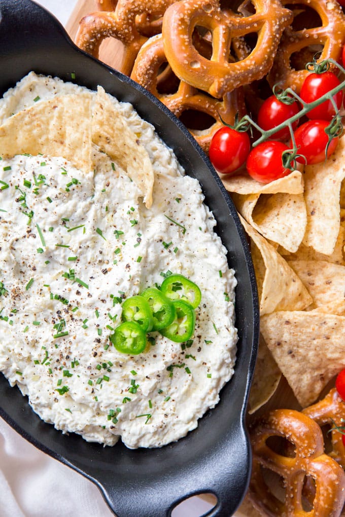 Jalapeno Artichoke Dip is creamy, spicy and perfect for dipping poolside this summer with your favorite chips, pretzels, veggies and crackers. An overhead shot of Jalapeno Artichoke dip with sliced jalapenos and chips