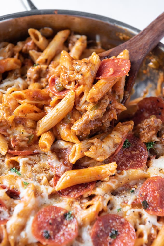 a wooden spoon, pasta, pepperoni, cheese, sausage for pizza pasta