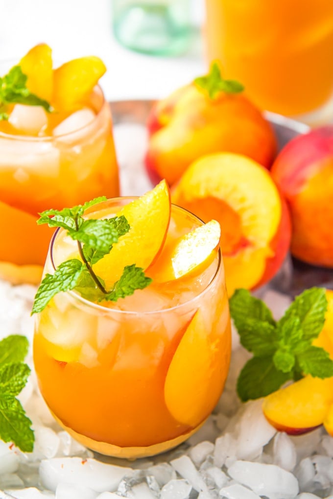 Two glass of peach sangria with crushed ice and fresh peaches